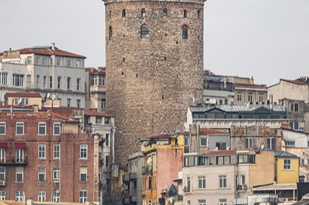 A historic stone tower surrounded by colorful buildings in a cityscape.