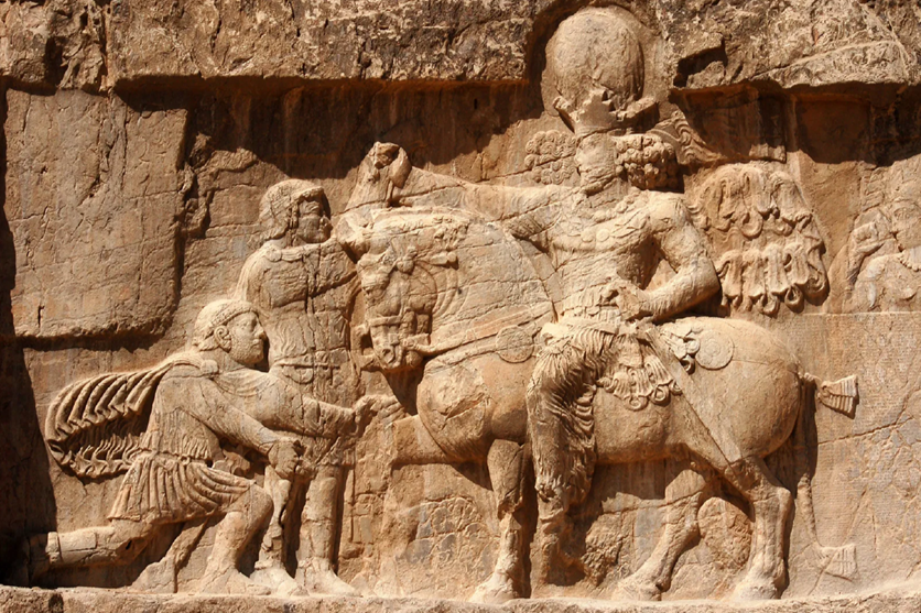 Ancient stone relief sculpture depicting a warrior on horseback, accompanied by soldiers.