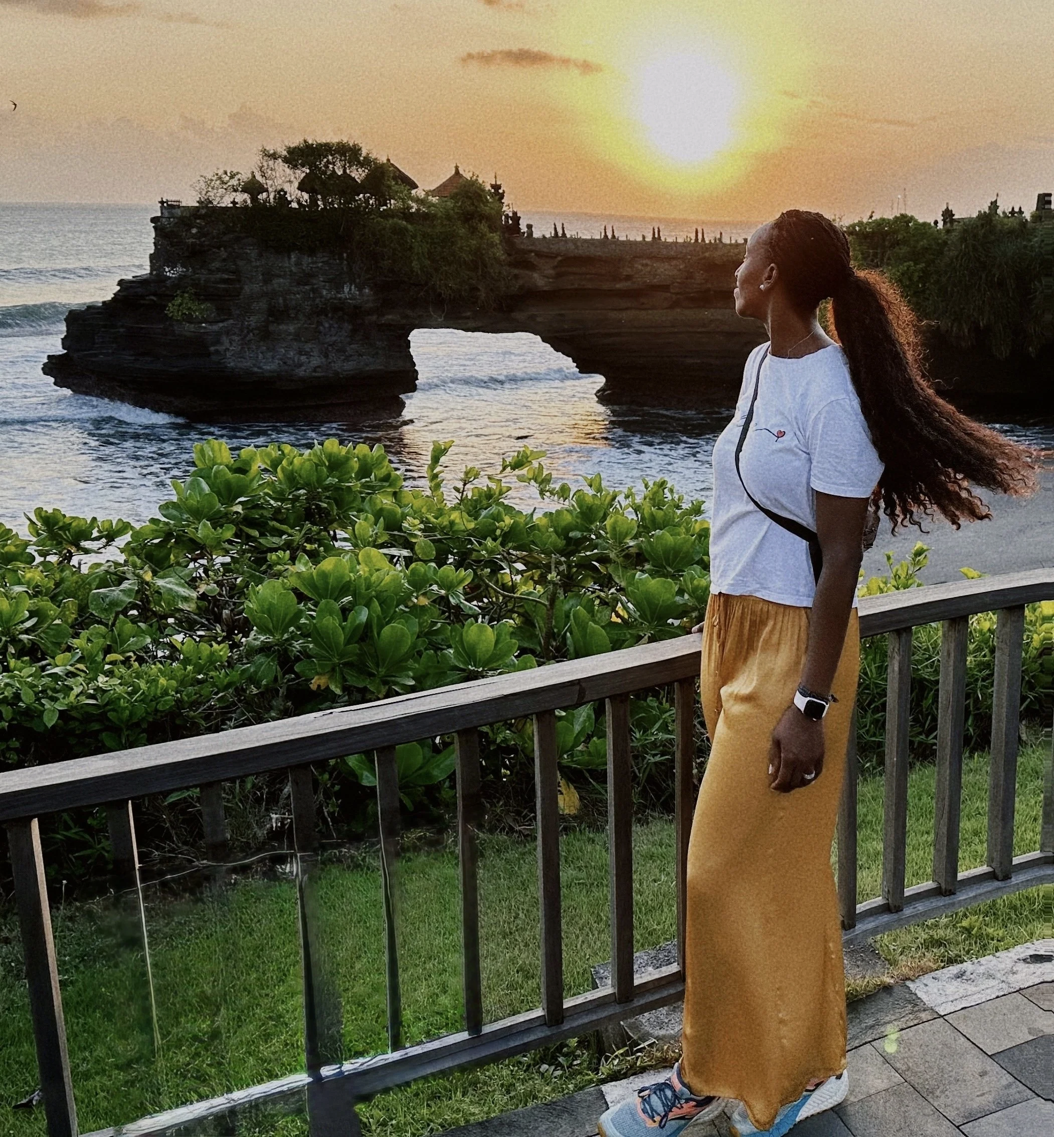Jessica, creadora de Jess in Flow, contemplando el atardecer junto a un templo costero en Bali.