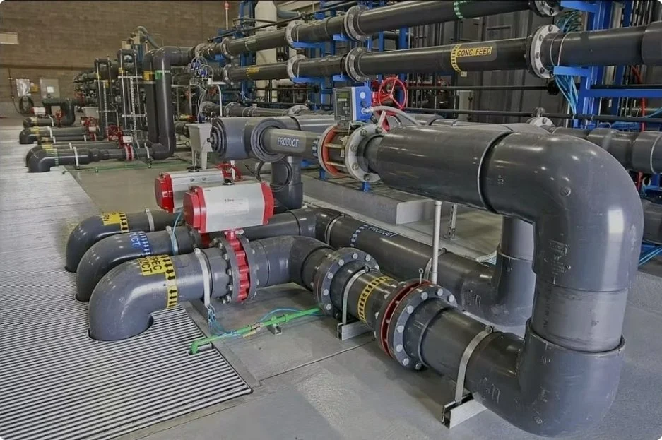 Industrial pipes and valves arranged on the floor in a factory or plant setting.