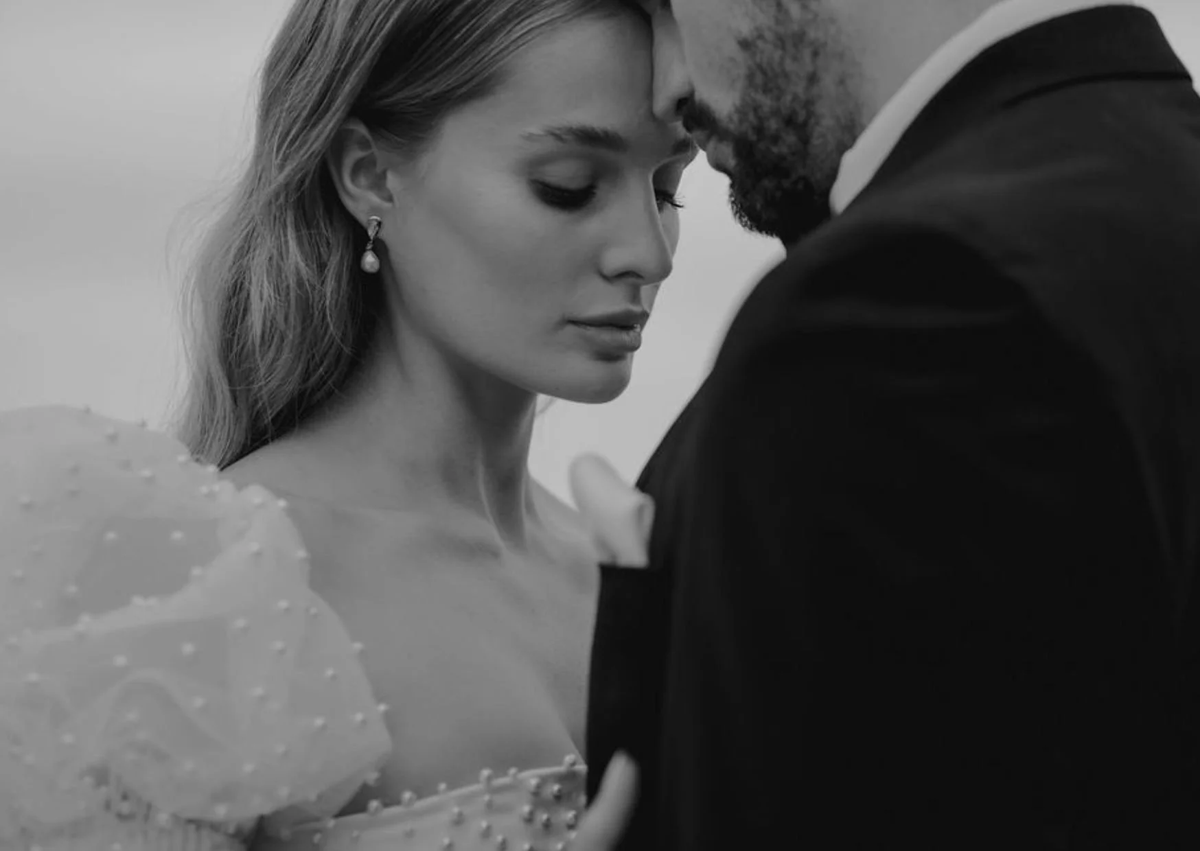 A black-and-white photo of a man and woman close together, touching foreheads with eyes closed, in a tender moment.