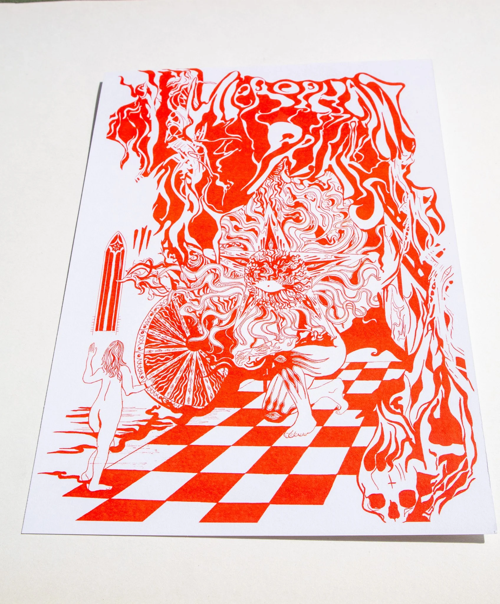 an angled photo of a print featuring a red and white psychedelic poster featuring a giant with the face of the sun surrounded by swirlin