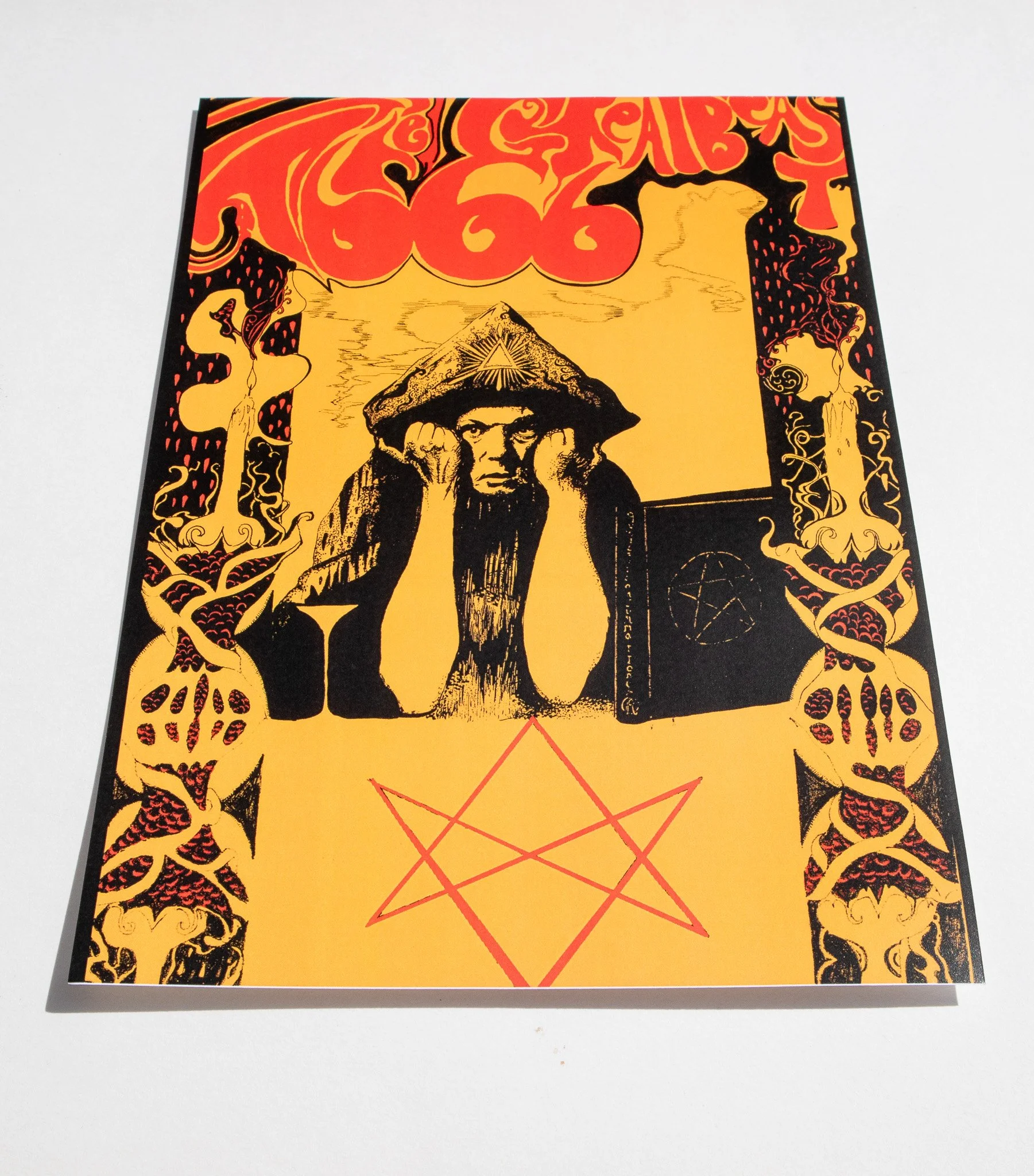 An angled photo of a print of a  black and yellow psychedelic portrait of Aleister Crowley featuring red text reading 'The Great Beast 666' in a gothic pen and ink style.