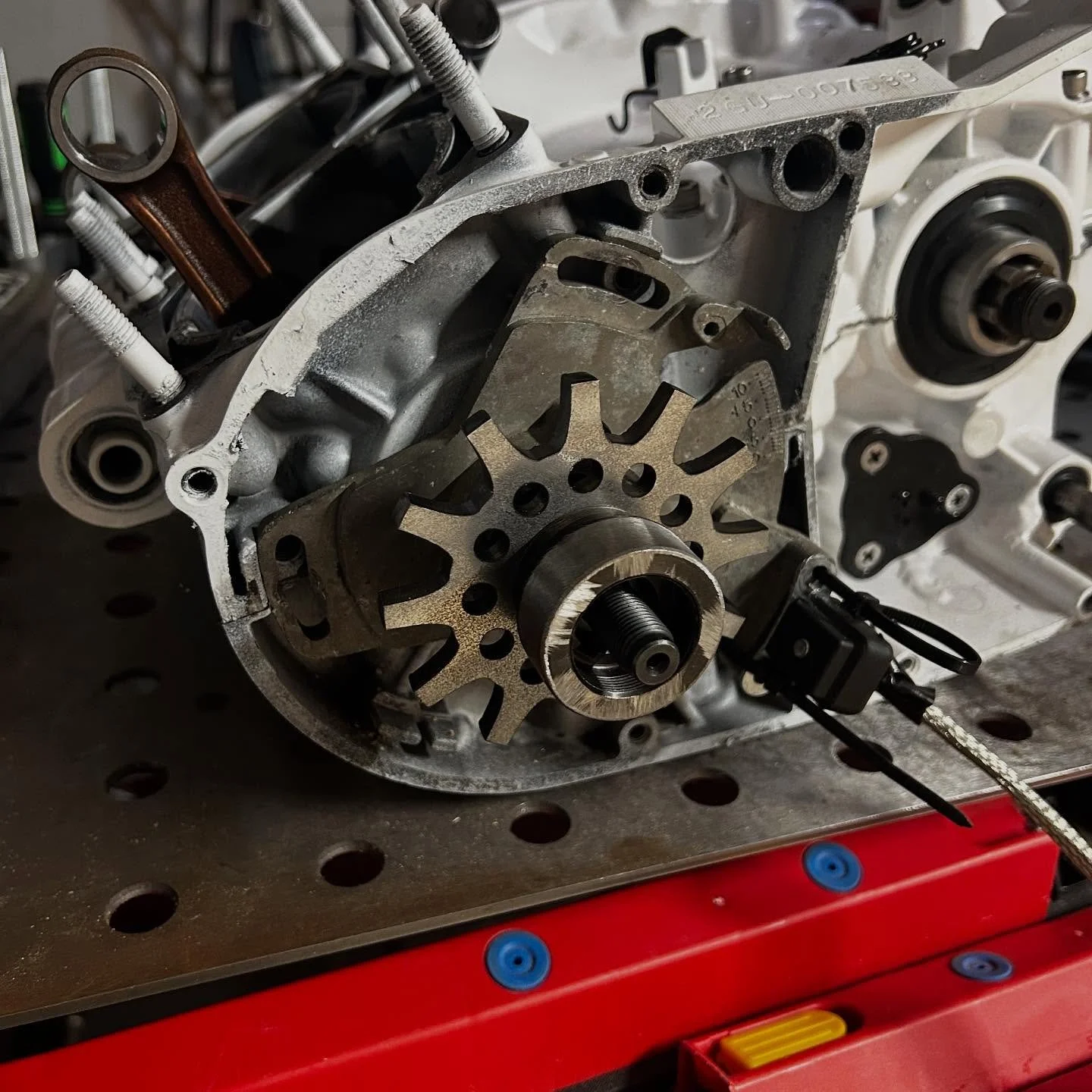 Close-up of a disassembled engine component with gears and mechanical parts on a workbench.