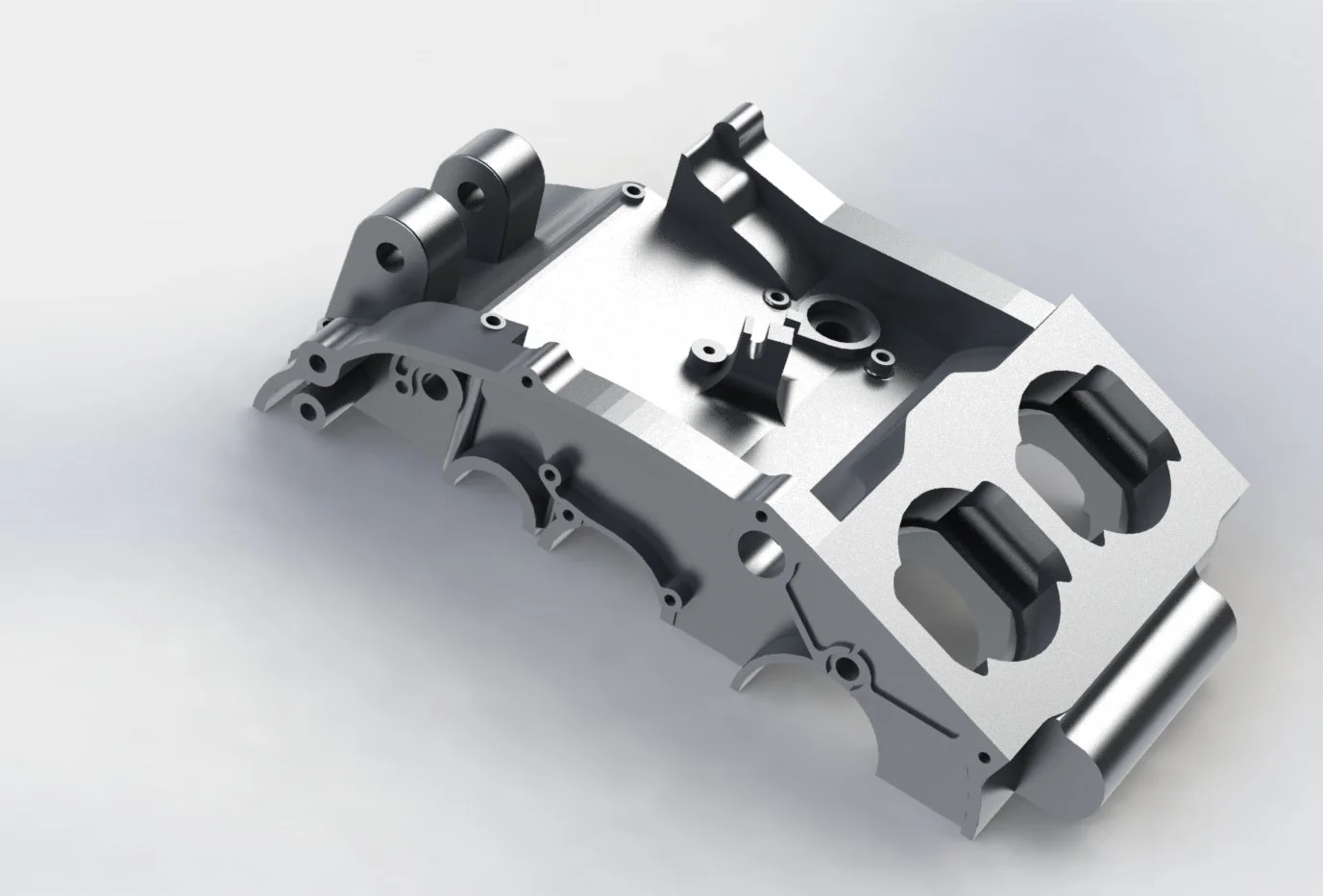 A metallic engine part with cylindrical sections and various holes and mounting points on a white surface.