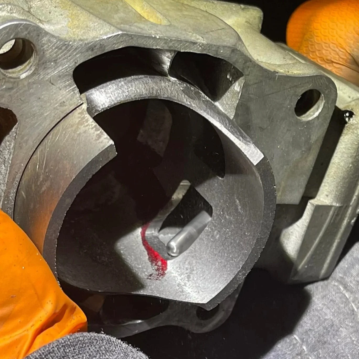 Close-up of a piston inside an engine cylinder, with visible wear and a red mark on the piston pin.