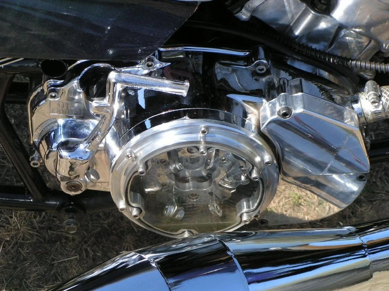 Close-up of a shiny, chrome motorcycle engine and exhaust pipe.