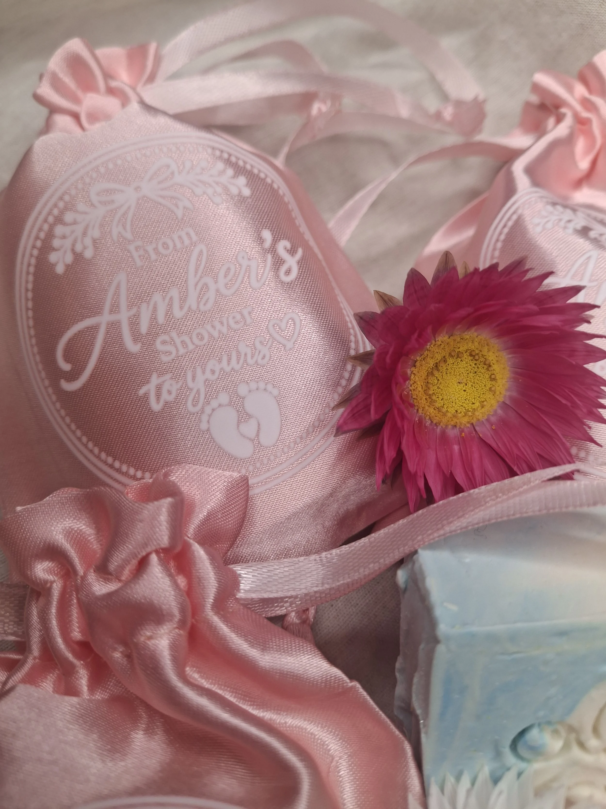 Close-up of a personalised baby shower favour bag with handmade soap and an everlasting flower