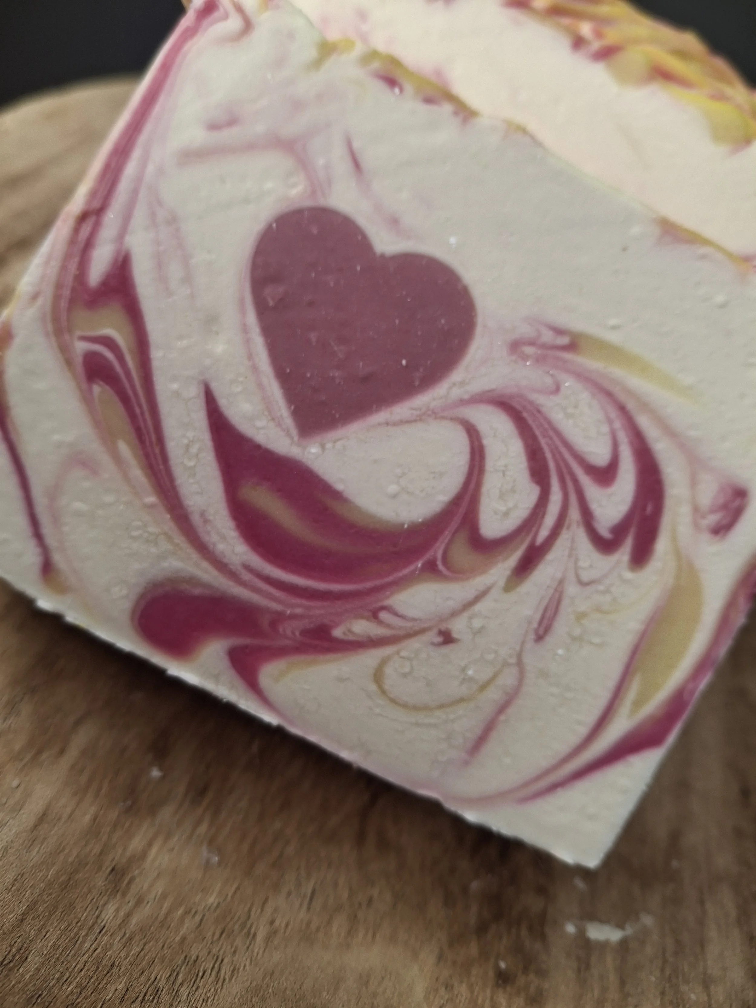 A beautiful handmade tallow soap featuring a sweet mauve heart, soft pink and ivory marbling and delicate golden accents. A luxurious, romantic floral soap.