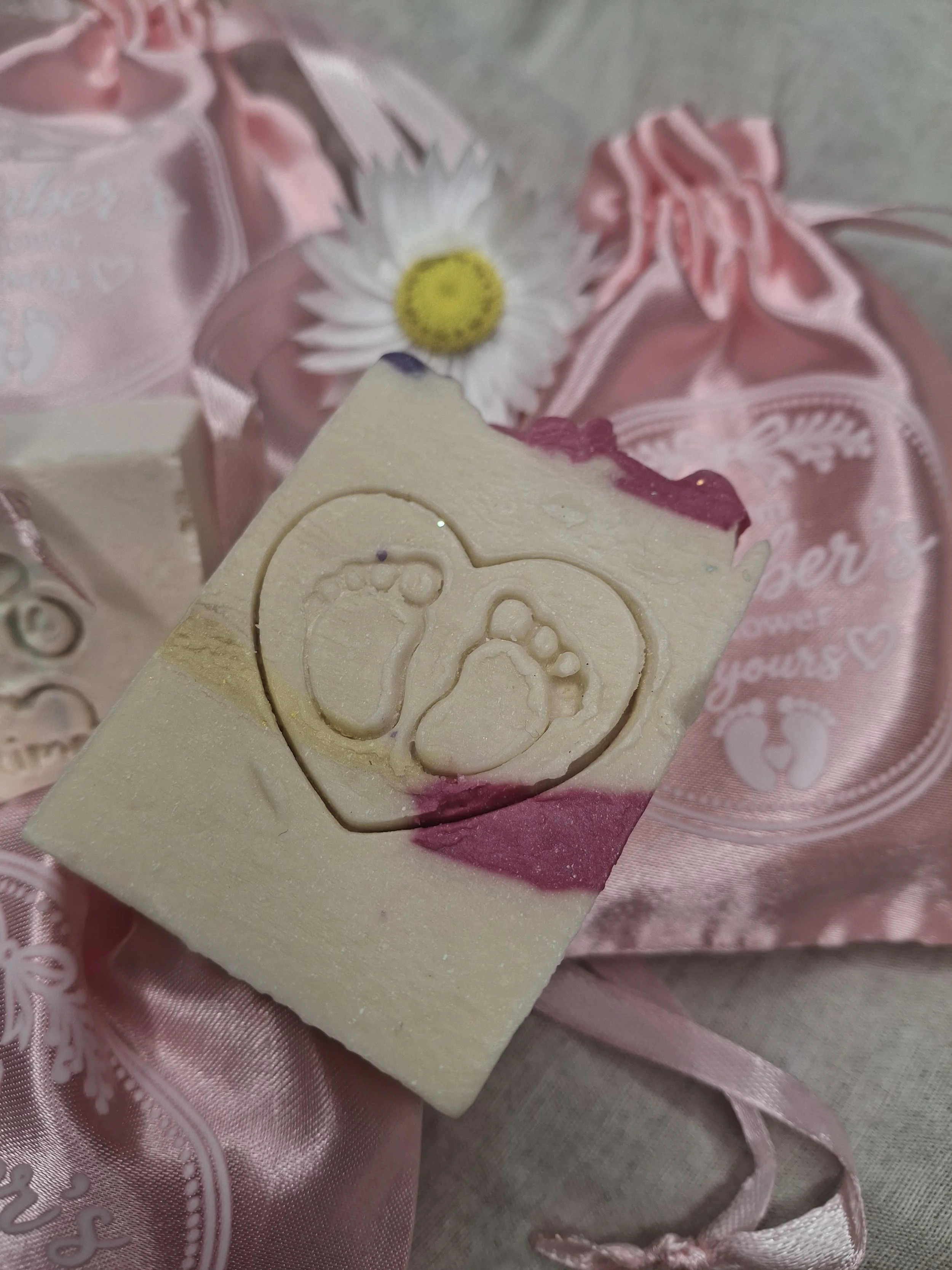 Handmade tallow soap baby shower favours in pink, purple and lemon with a baby footprint heart design.