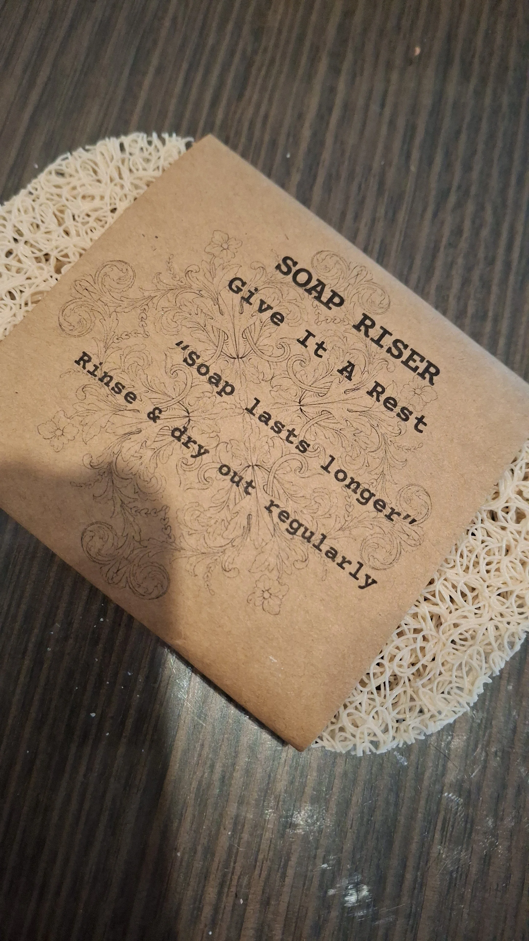 Cream mesh soap riser with kraft paper sleeve, designed to keep handmade soap elevated and help it dry between uses.