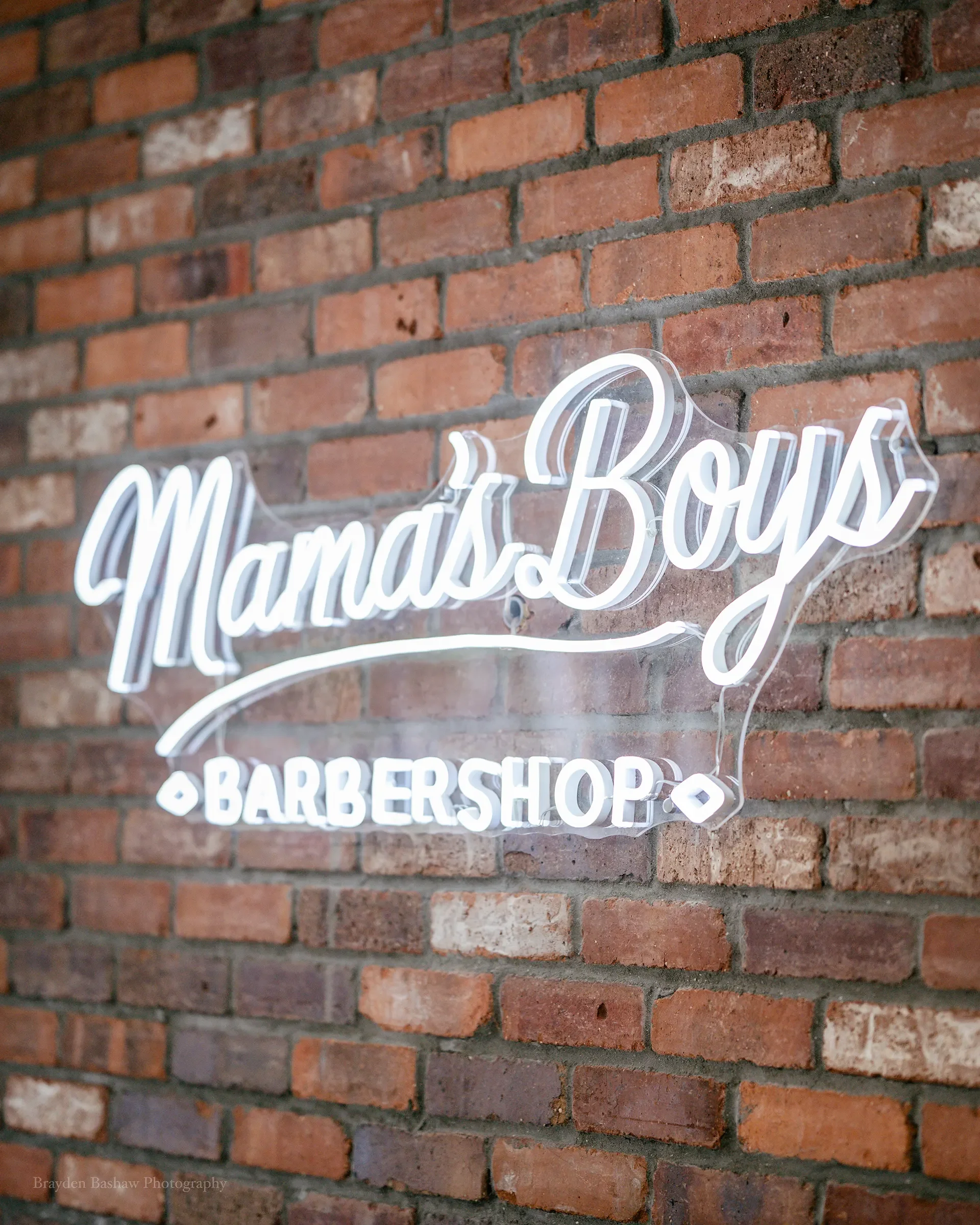 Mama's Boys Barbershop logo sign on a brick wall.