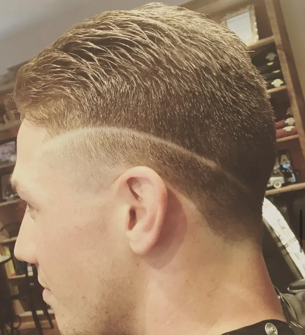 Close-up side view of a man's haircut featuring a fade with a textured top.