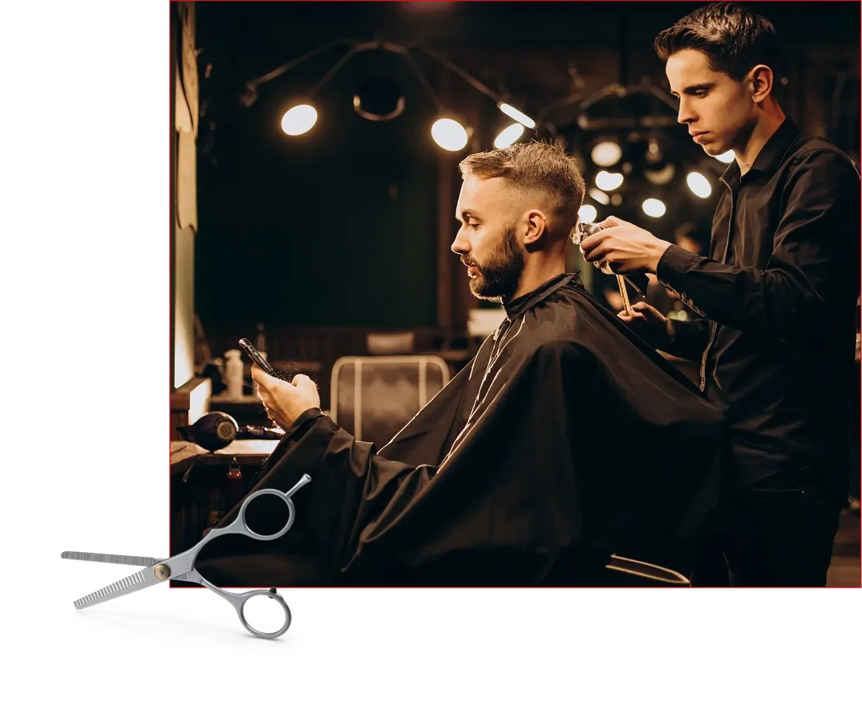 A man with a beard sitting in a barber chair at a barbershop, looking at his phone, while a barber cuts his hair. The barber is standing behind him, focused on the haircut, in a modern salon with warm lighting.