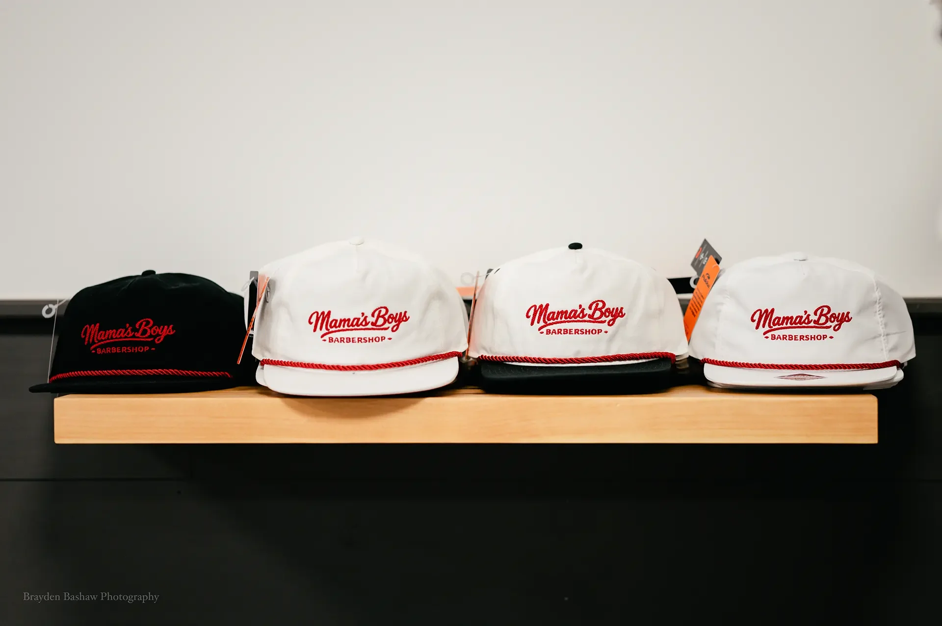 Mama's Boys Barbershop branded snapback hats and caps on display.
