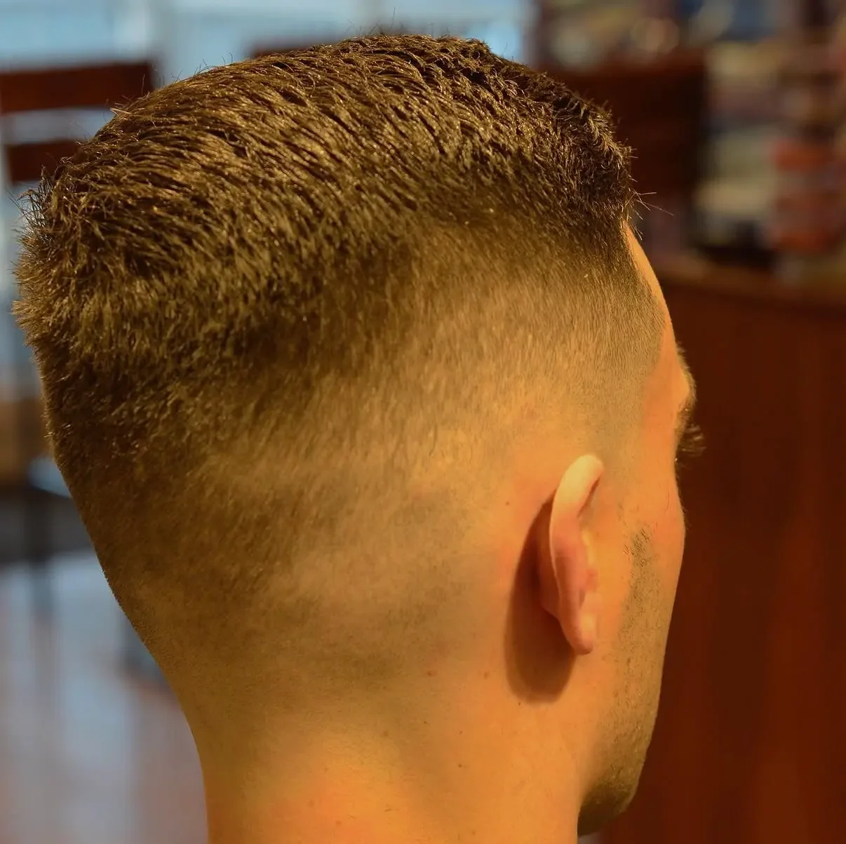 Back and side view of a man's freshly cut short hairstyle, with a fade haircut and textured top.