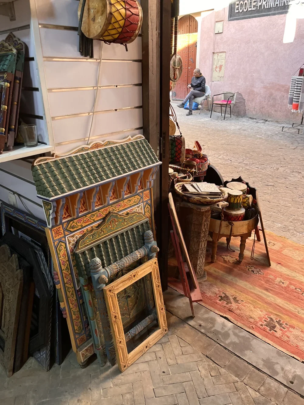 Intricate hand-painted wooden frames leaning on the ground near the entrance to a stall in a Moroccan souk.