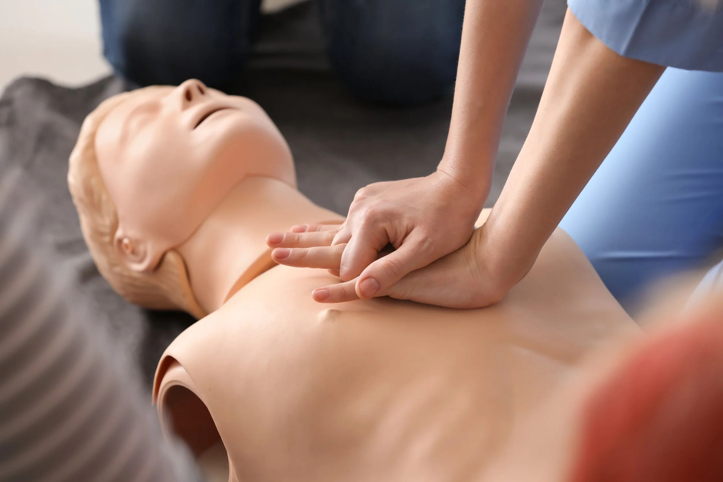 A person performing CPR on a mannequin during a training session.