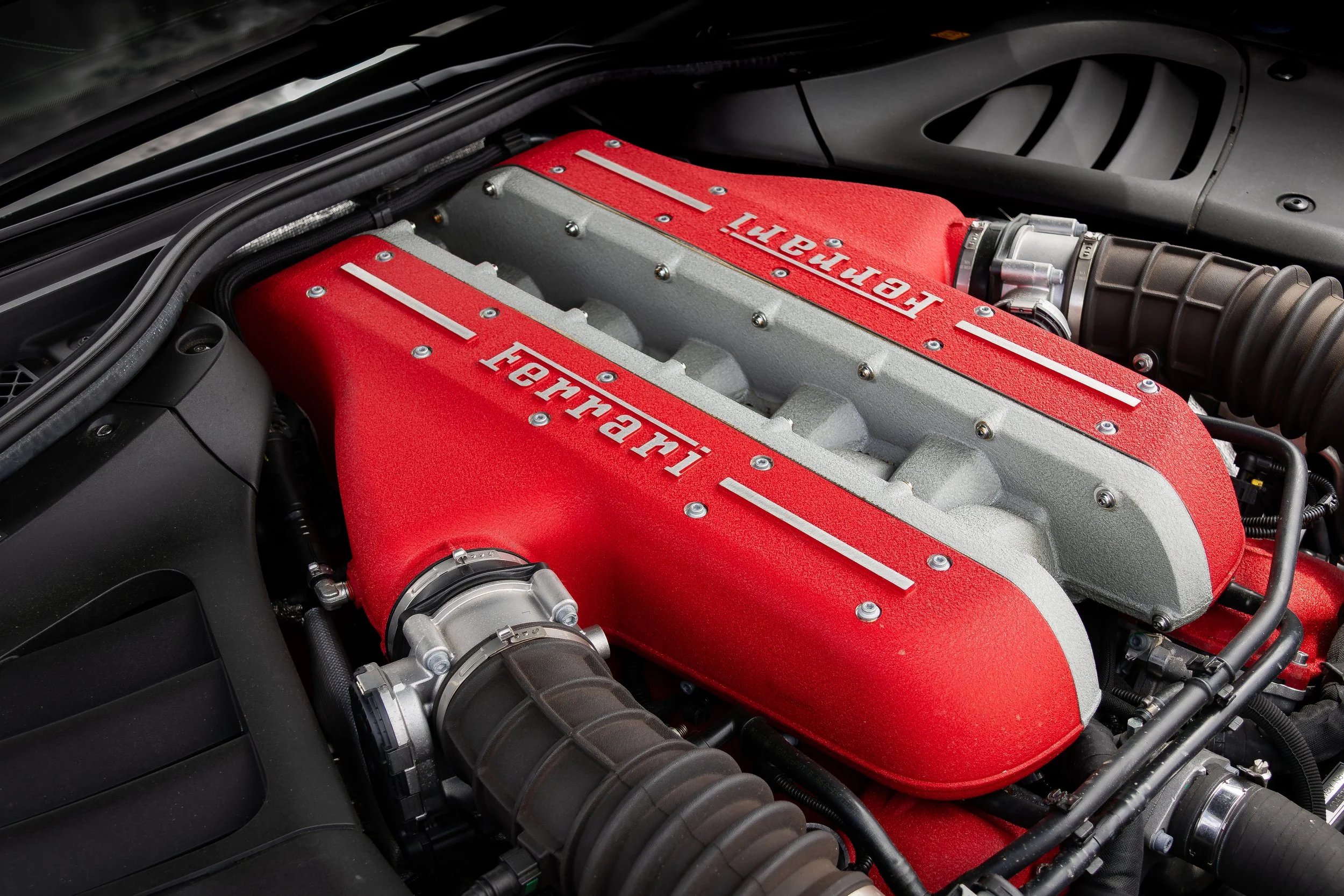 Close-up view of a Ferrari FF engine with a red intake manifold and silver accents.