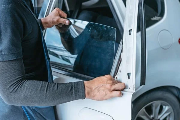 Person installing or replacing a window on a white vehicle.