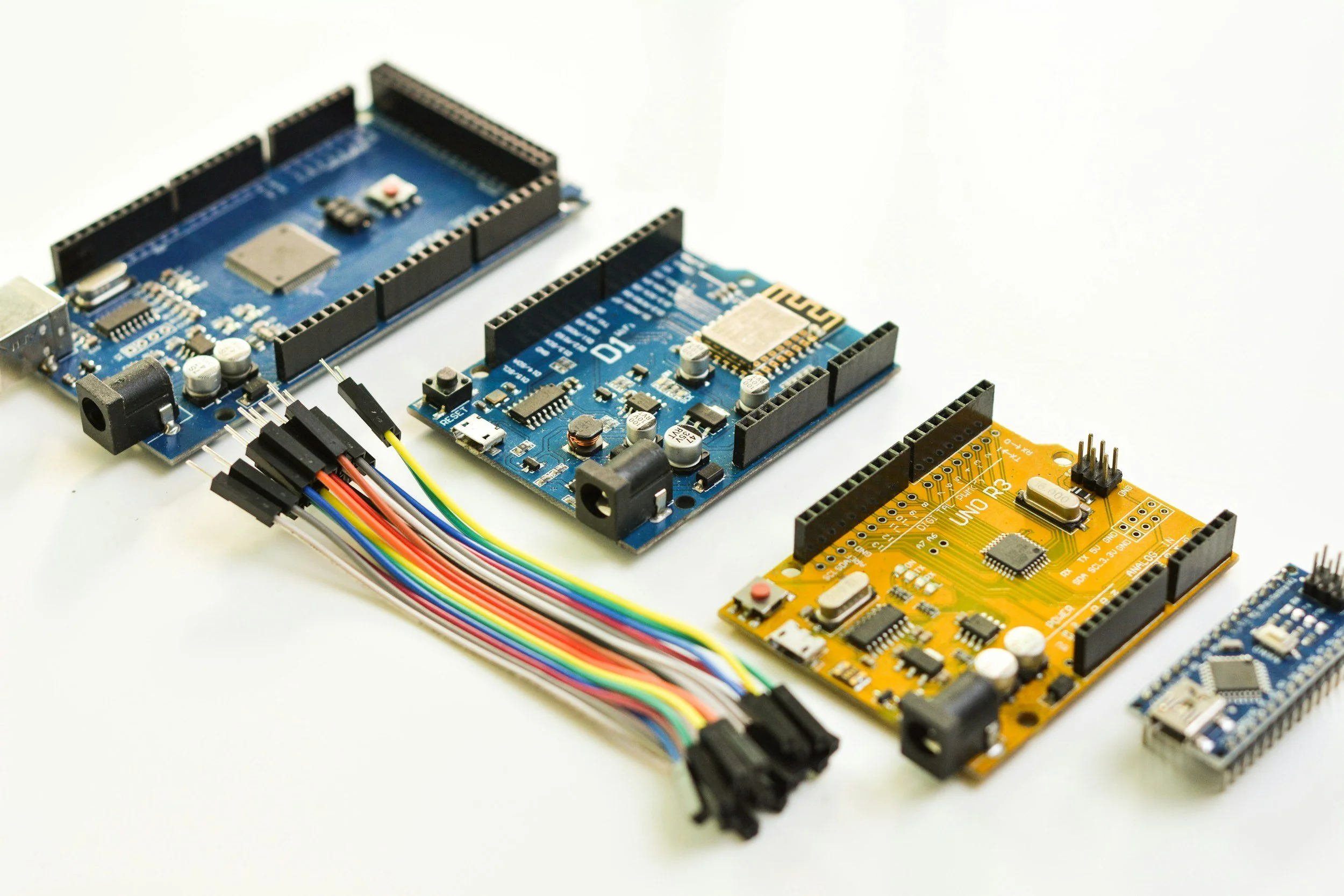 Close-up of multiple colorful electronic circuit boards and microcontrollers on a white surface.
