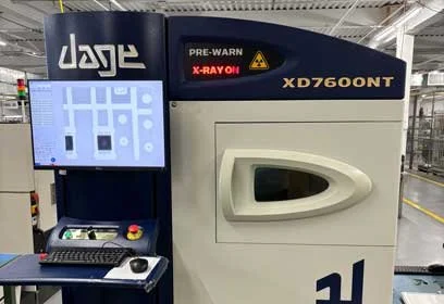 Industrial X-ray machine labeled 'XD7600NT' with a digital monitor and control panel in a factory setting.
