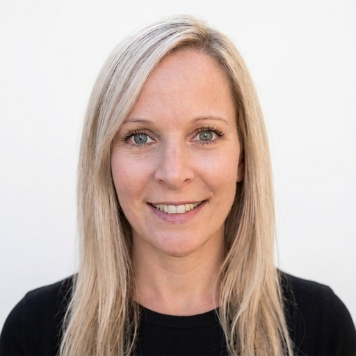 A woman with long blonde hair, smiling, wearing a black top against a white background.