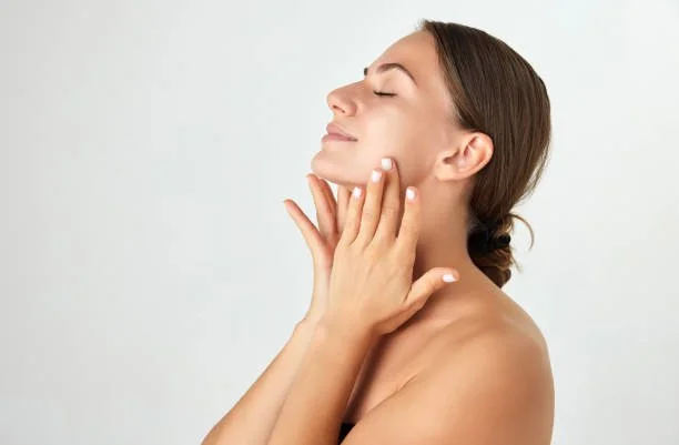 A woman gently touching her face with her eyes closed, appearing relaxed.
