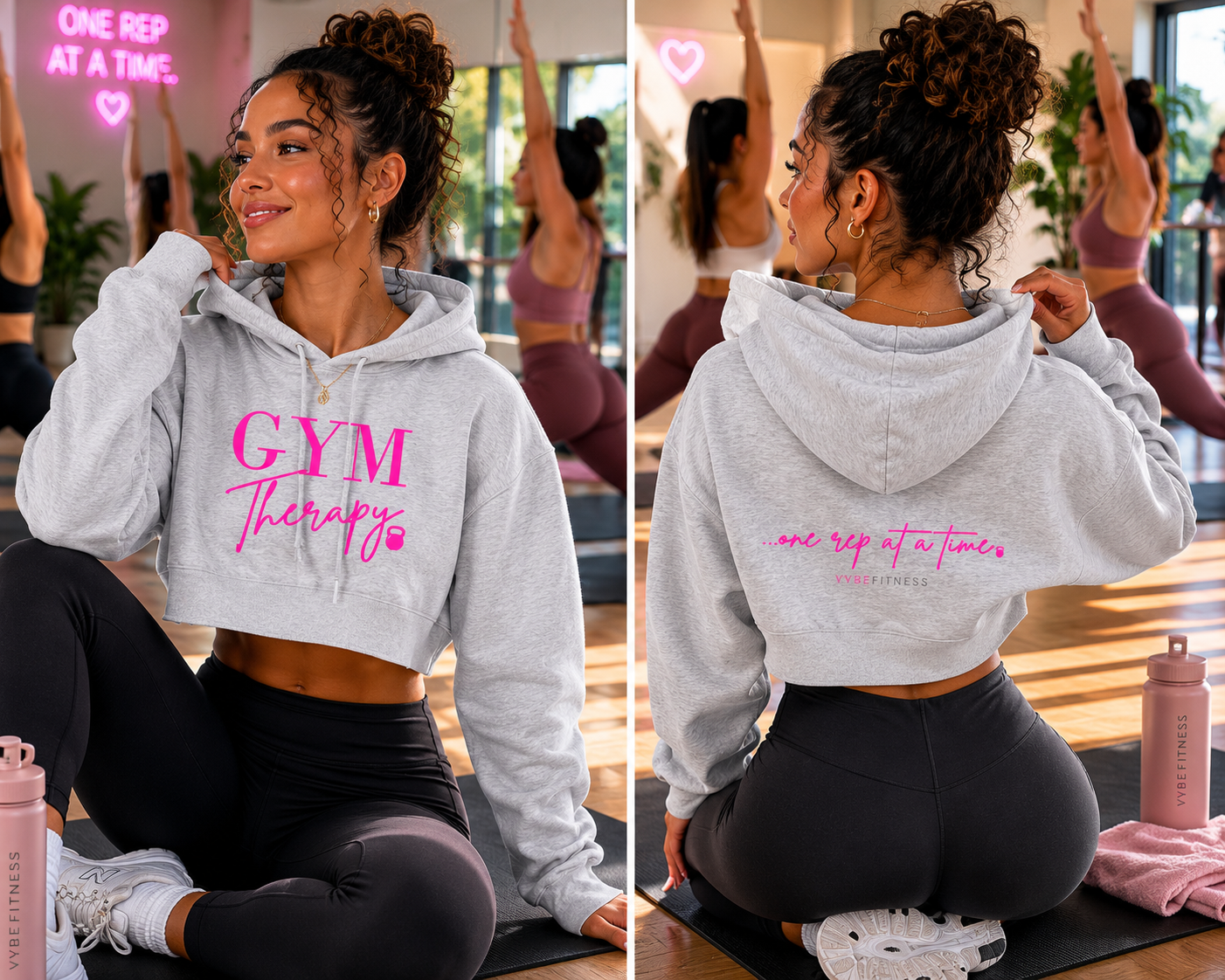 Young woman with curly hair in a gray hoodie that says 'GYM Therapy' in pink, smiling in a gym studio with other women exercising in the background, pink neon sign reading 'ONE REP AT A TIME' on the wall, water bottle on the floor.