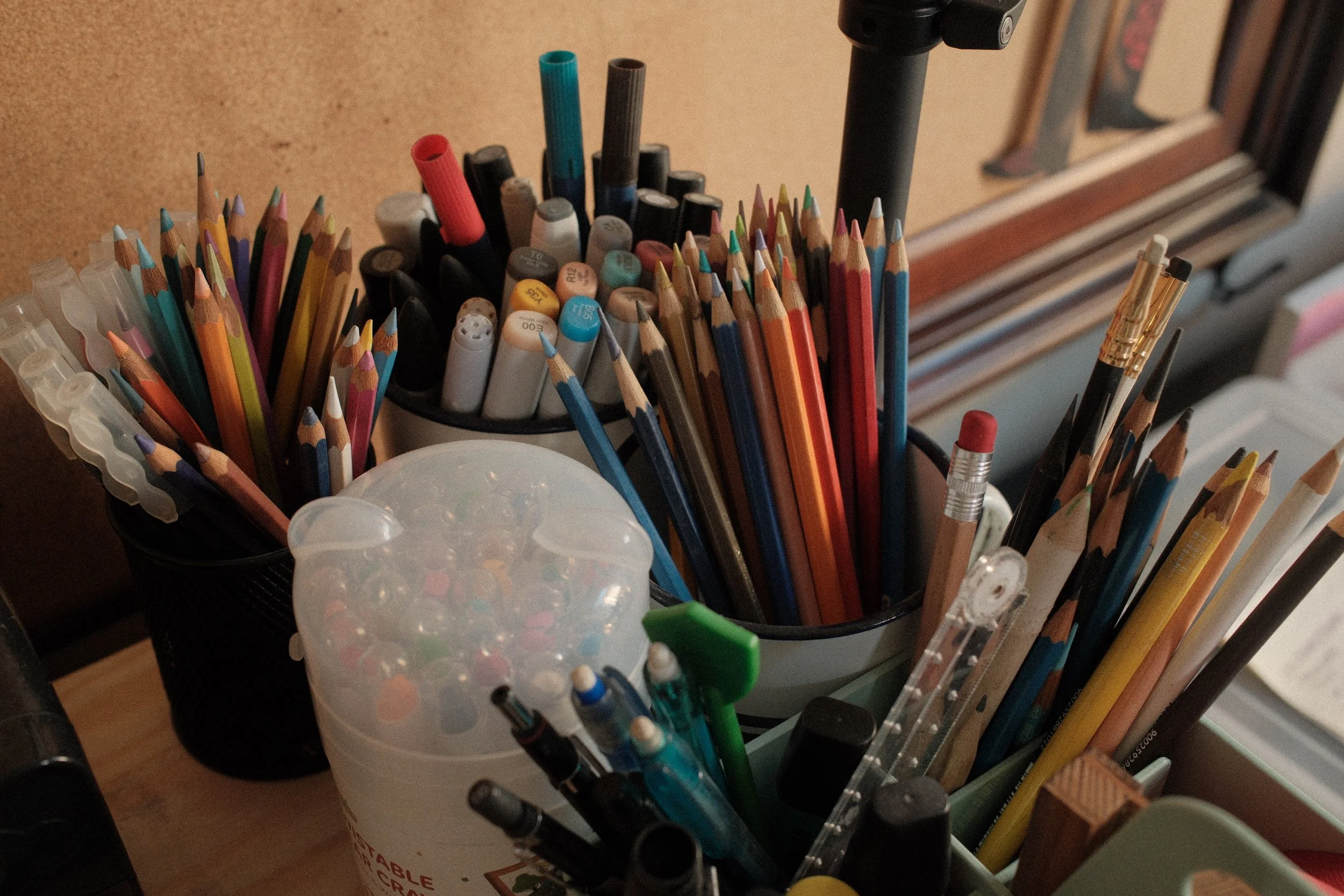 Close-up of crayons, pencils, markers, and other traditional art materials used for illustration.