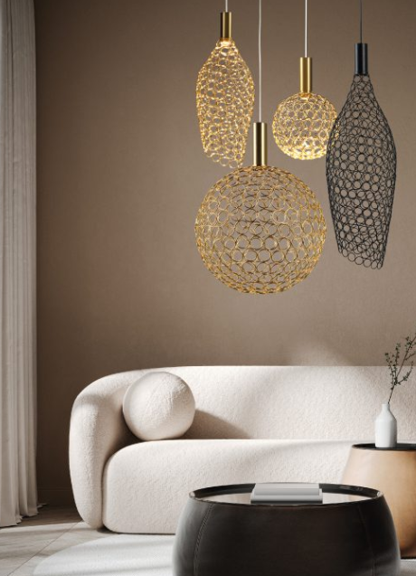 Modern living room with a white curved sofa, round decorative pillow, black coffee table, white vase with small plant, and pendant lights with gold and black geometric designs hanging from the ceiling.