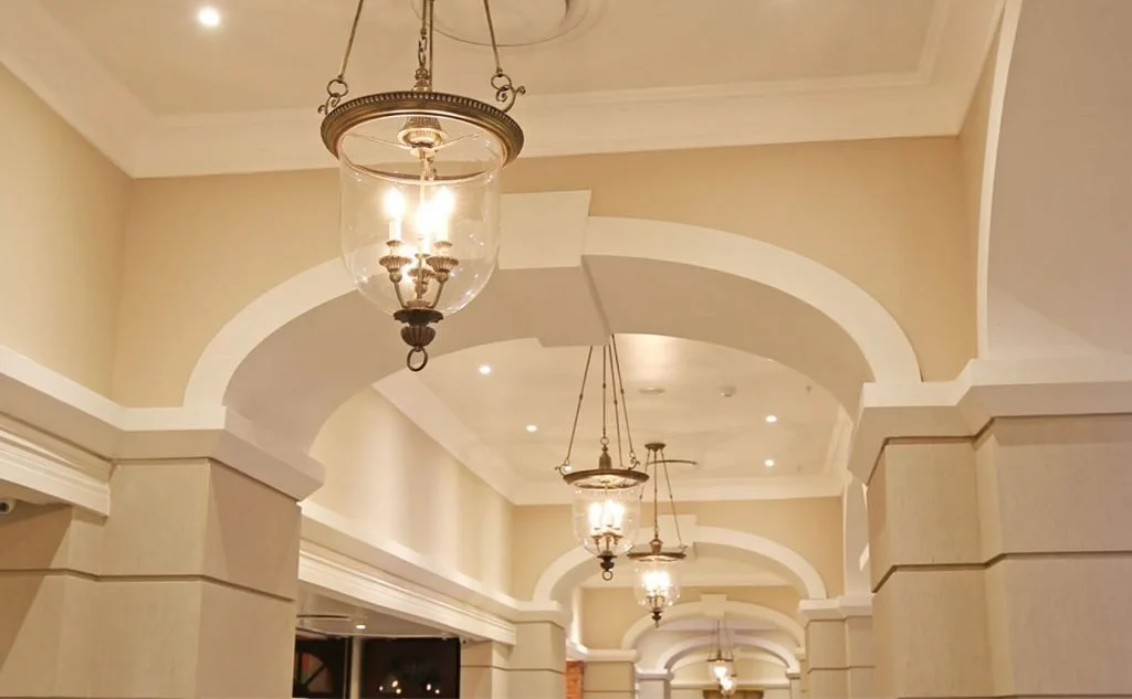 Interior hallway with arched ceilings, beige walls, and hanging lantern-style light fixtures.