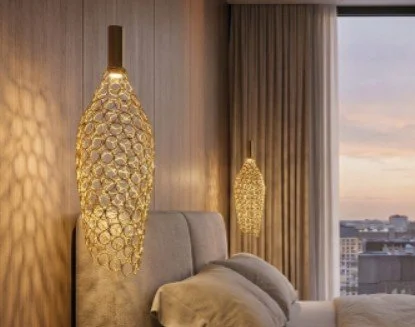 Luxury bedroom with two gold honeycomb-shaped pendant lights, a gray upholstered headboard, and beige curtains, overlooking a city skyline at sunset.