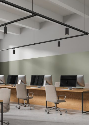 Empty modern office workspace with desktop computers and beige office chairs.