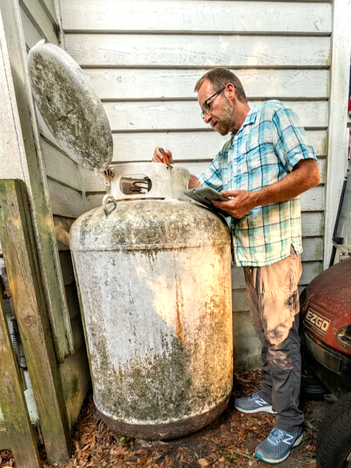 Inspector testing aboveground propane tank for leaks.