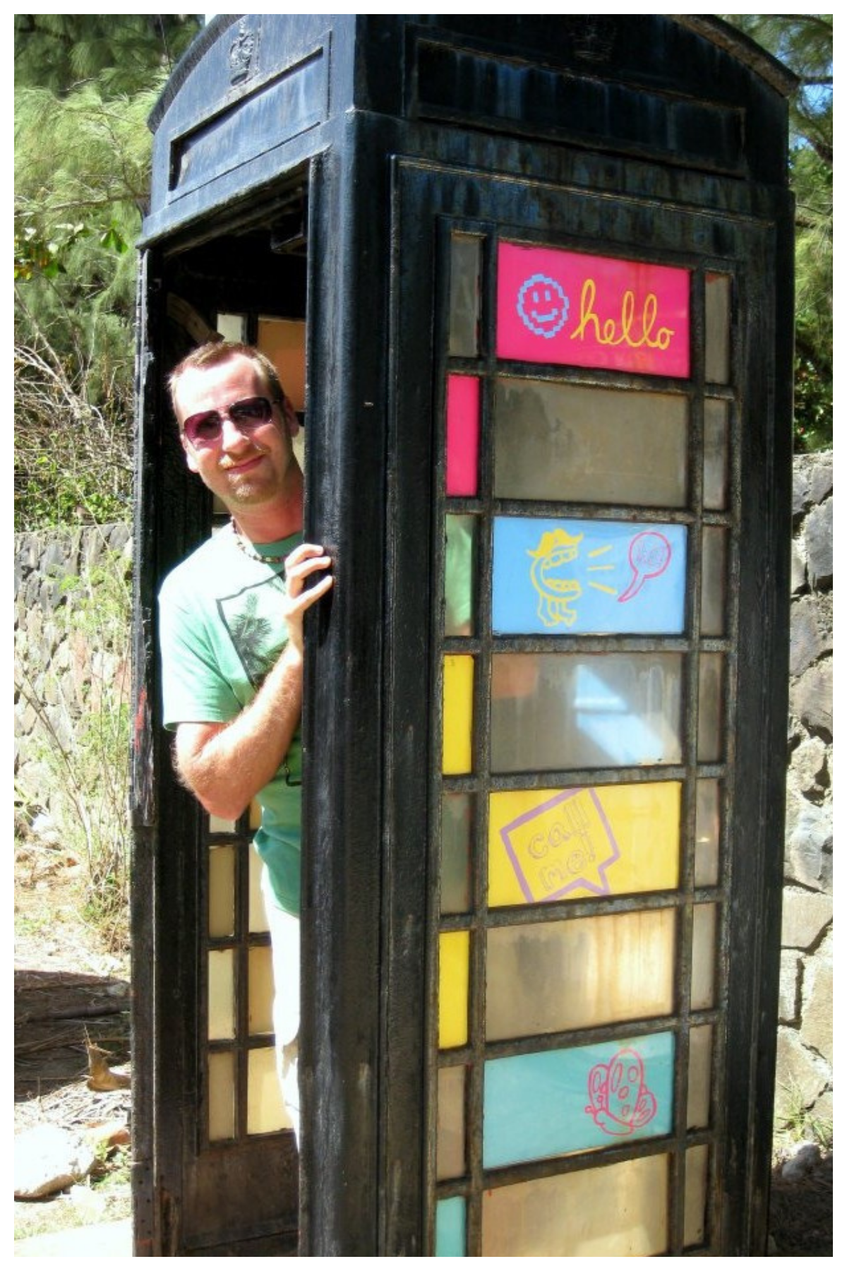 Home Inspector Shawn DePenning peeking out of a colorful vintage phone booth.