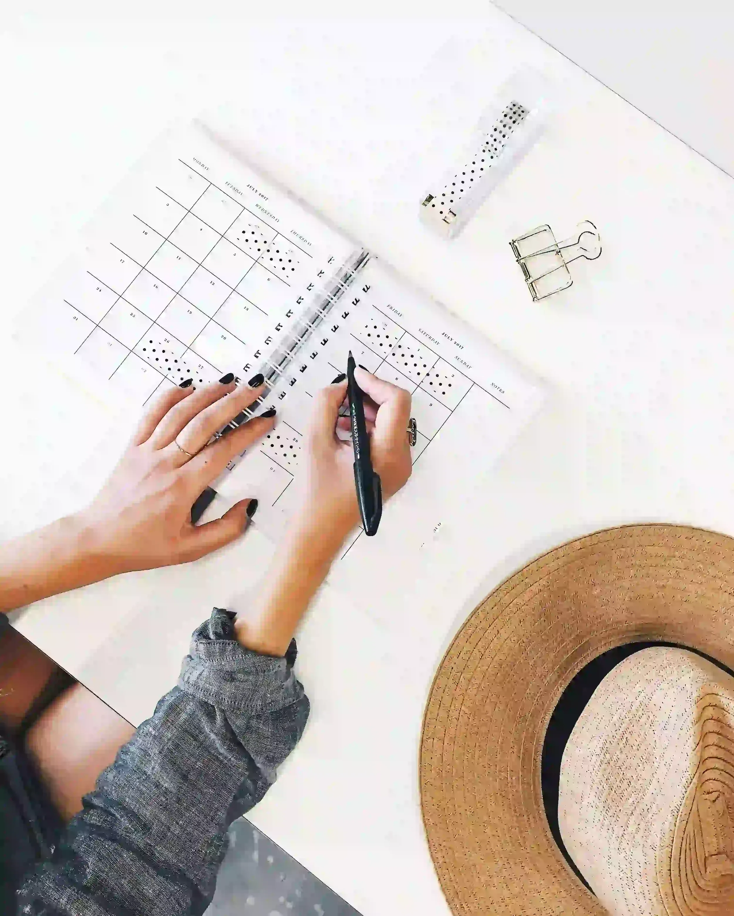Person writing in a planner at a bright desk, suggesting organization, productivity, and support for perfectionism.