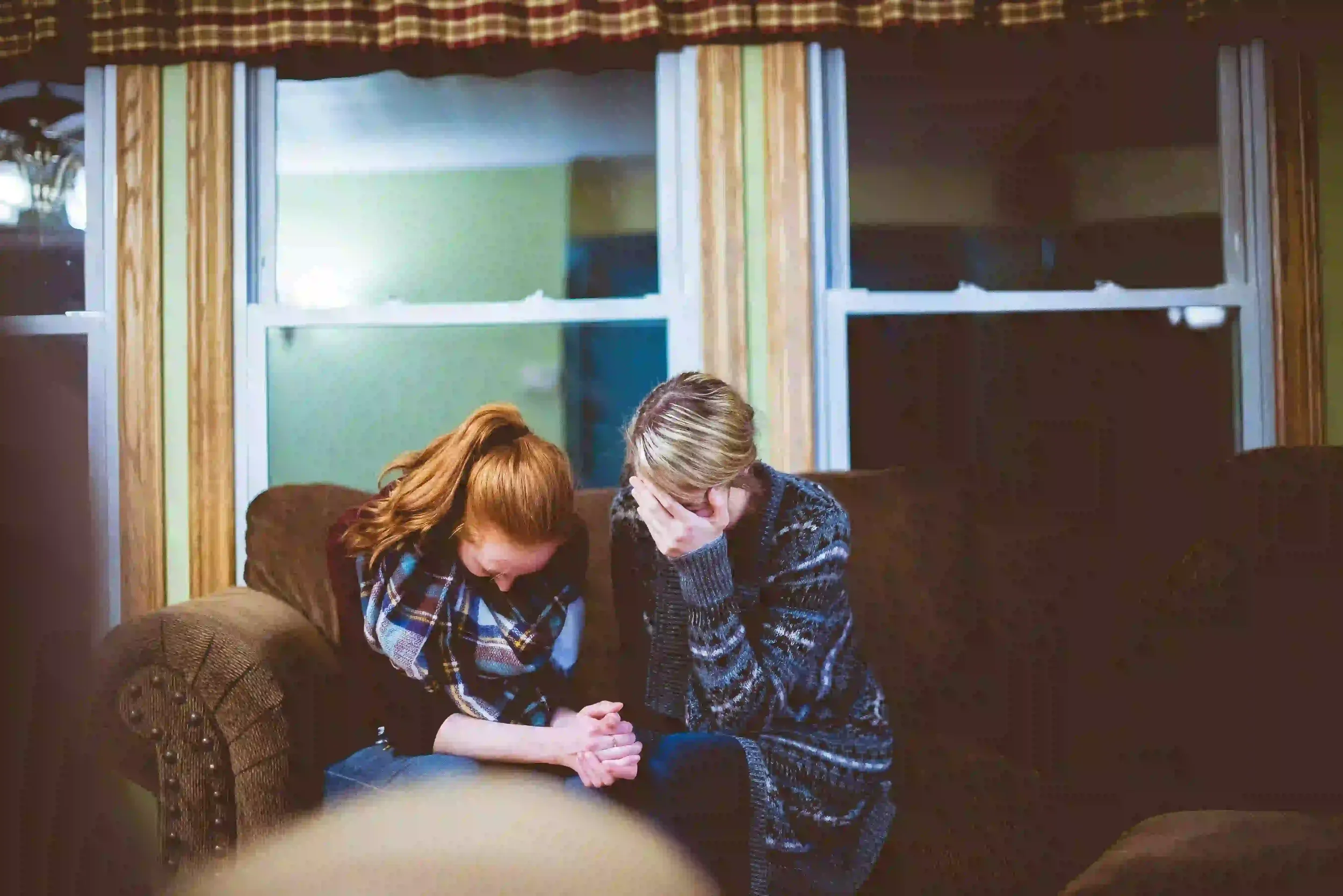 Two people sitting close together on a couch during an emotional relationship conversation, suggesting support, stress, or couples therapy.