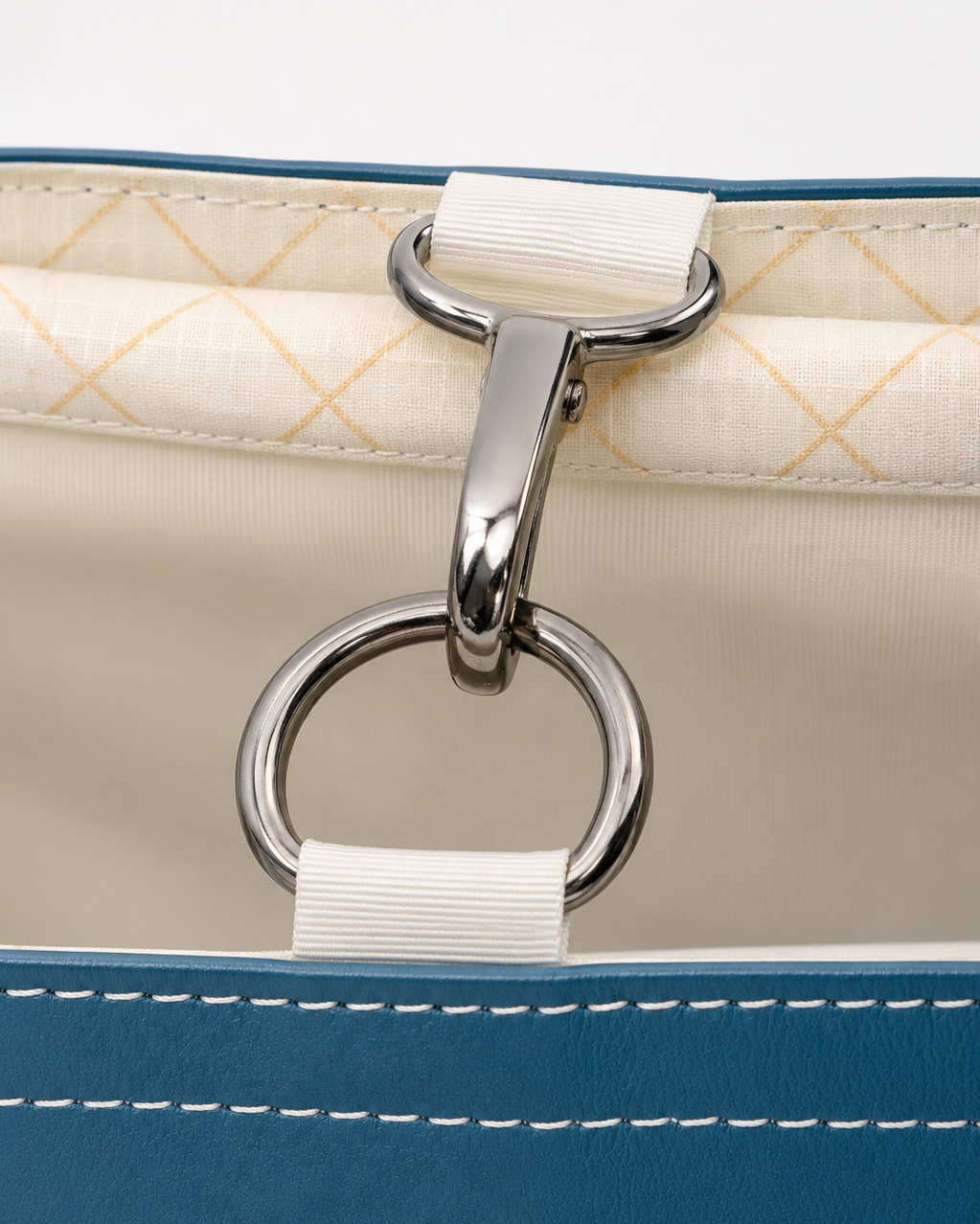 Close-up of a metal ring and hook on the inside of a blue and cream fabric bag.