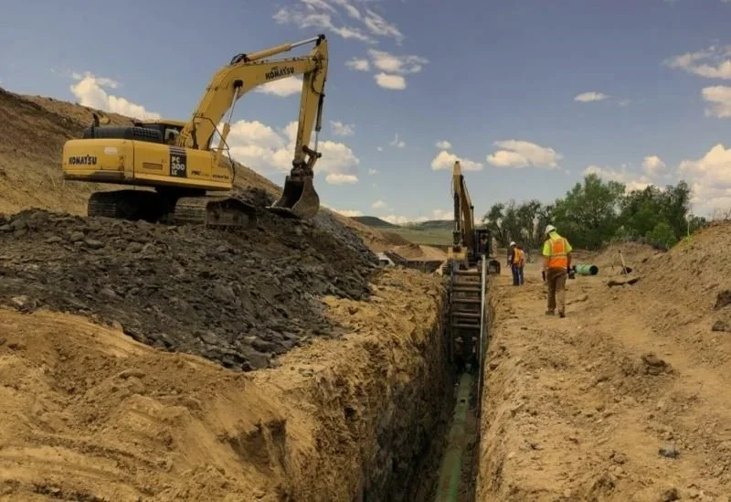 Construction site with an excavator and workers working on underground pipeline installation in OKC.