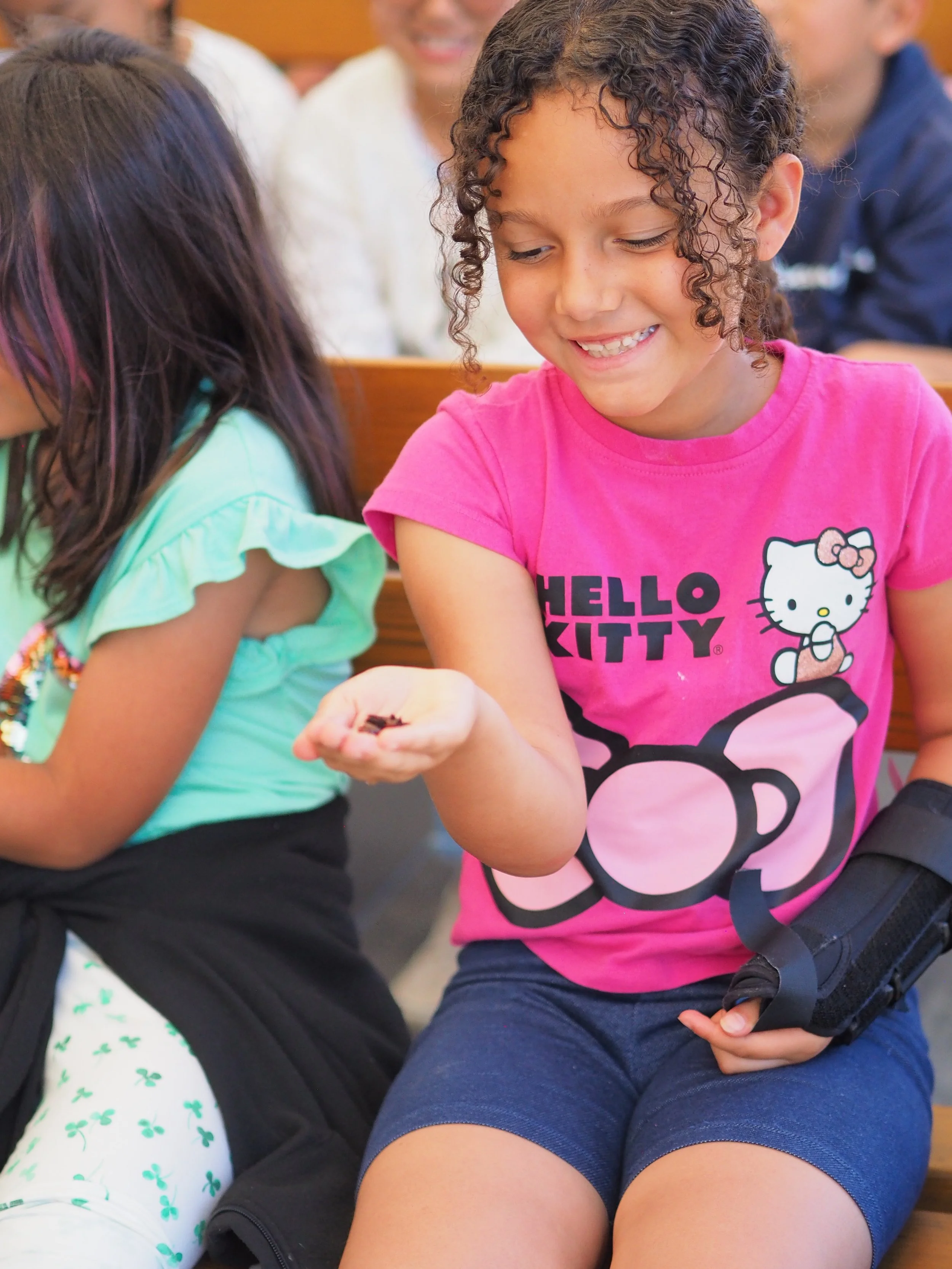 girl in Hello Kitty t-shirt holding an insect