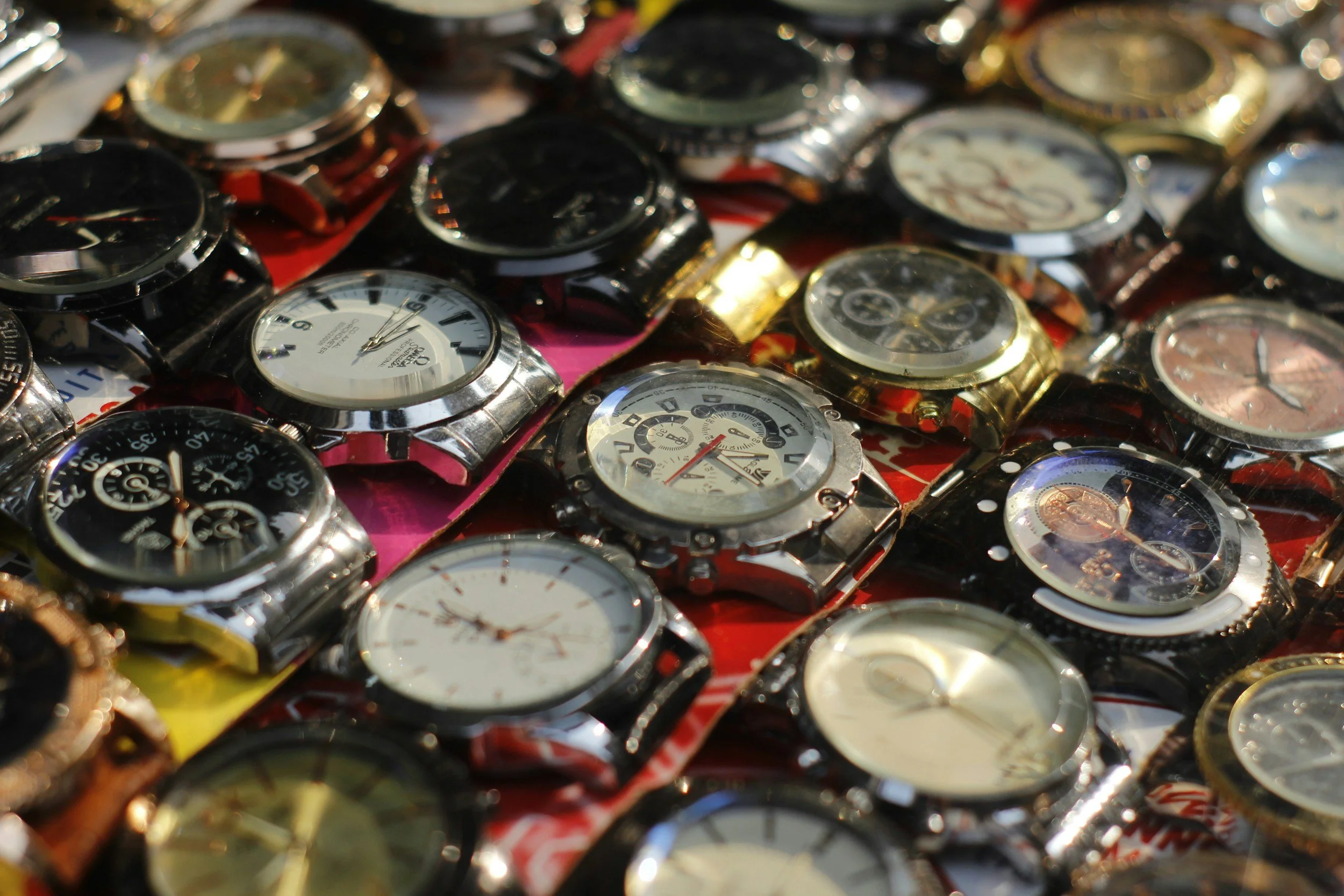 A collection of various wristwatches piled together, displaying different styles, colors, and designs.