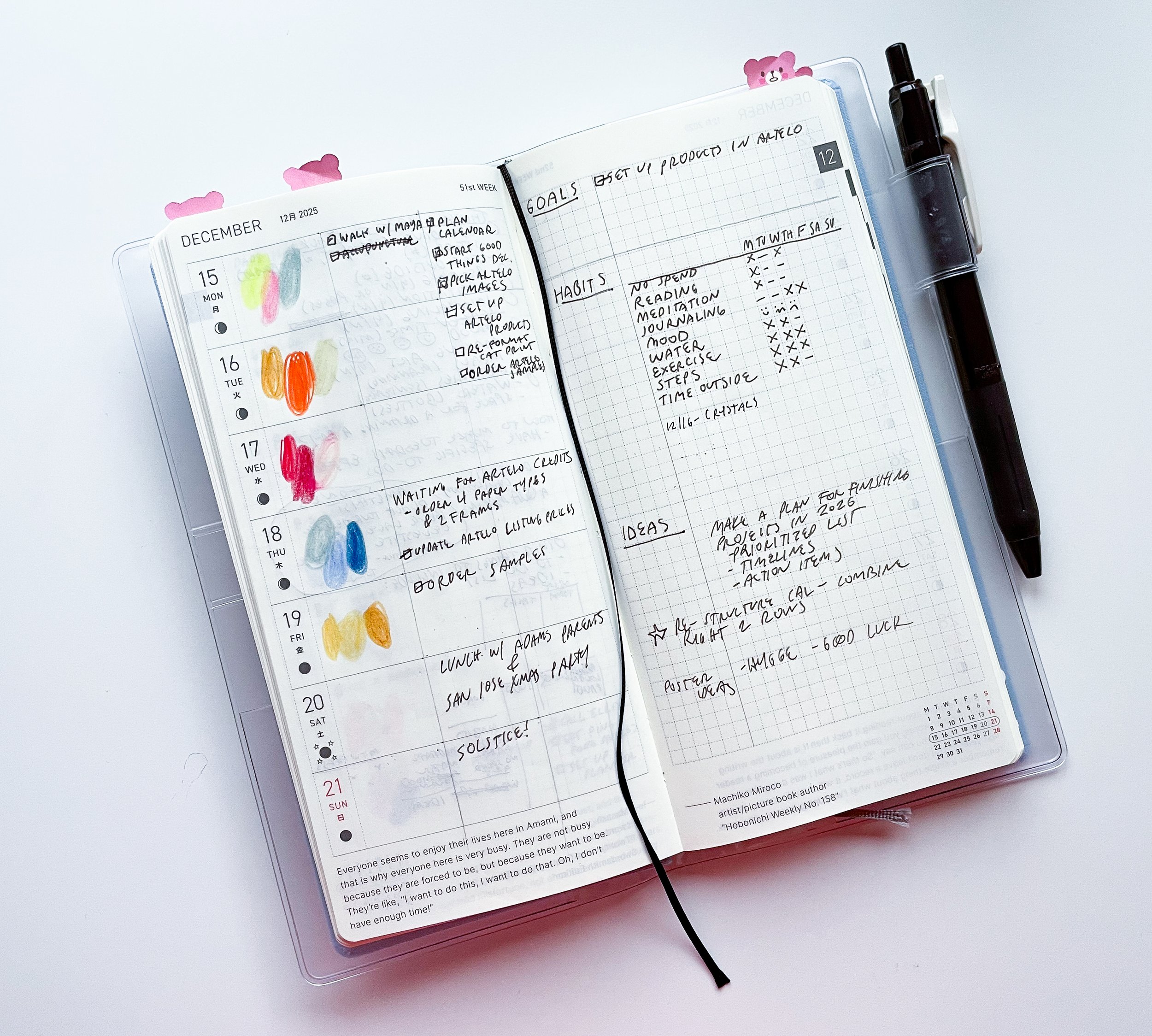Open planner with handwritten notes, colored markers, and a black pen clipped to the right side. The planner shows dates in December 2025, with colorful markings and lists of plans and goals.