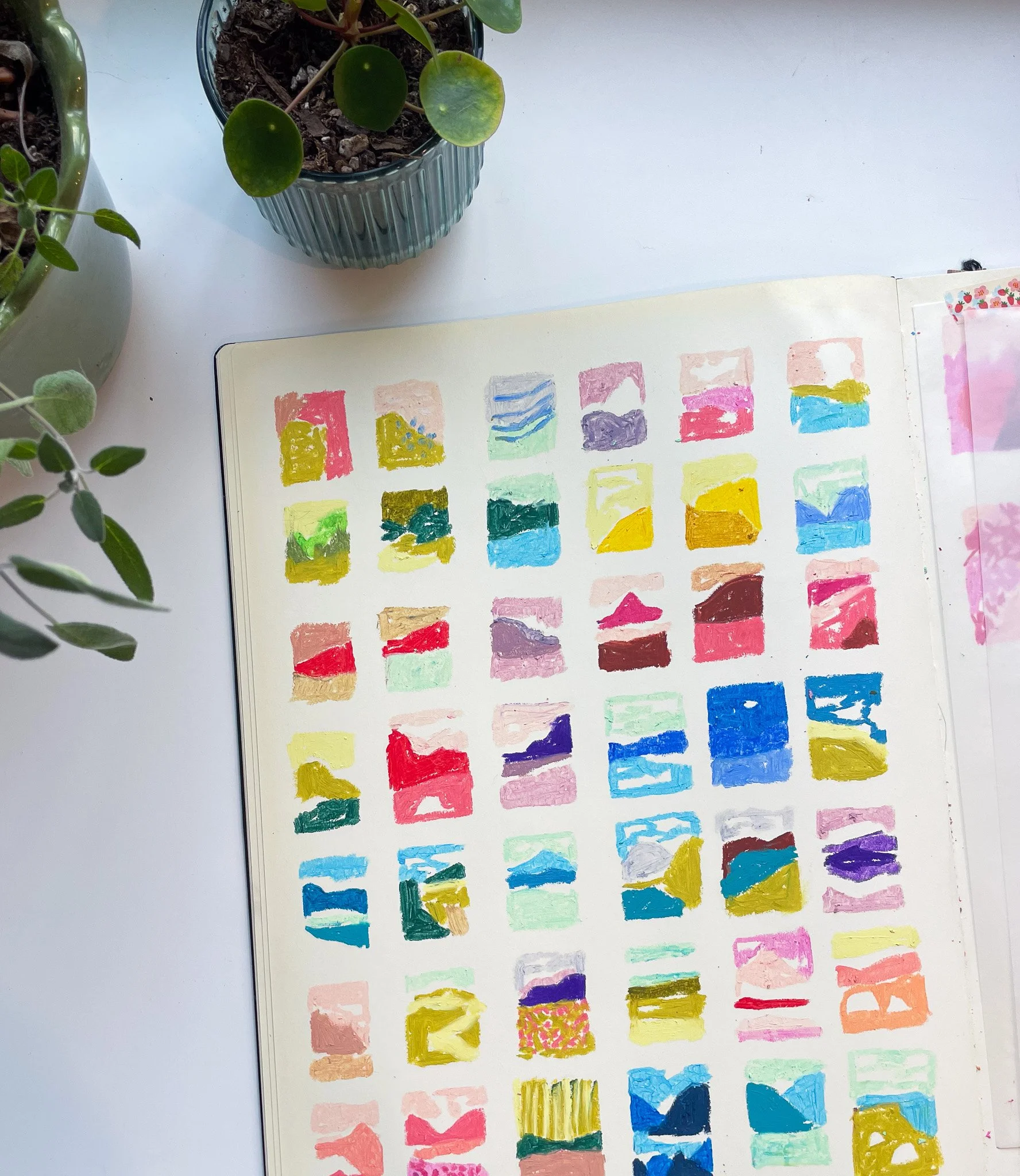 A watercolor palette displaying various colors arranged in small squares on a large sheet of paper, with colors ranging from pinks and reds to blues, greens, and yellows.