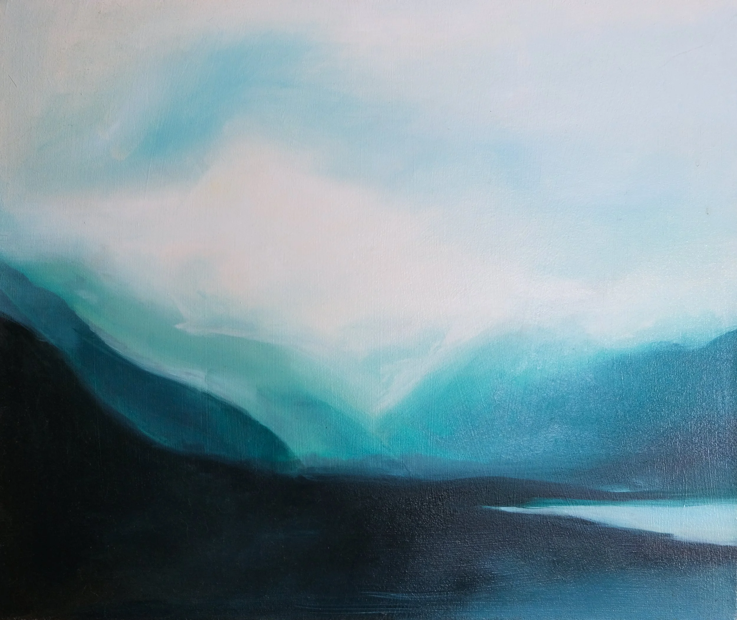A landscape photograph capturing a water body with gentle ripples, the sky with a gradient from blue to soft pastel pink, and dark silhouettes of mountains or hills in the foreground.