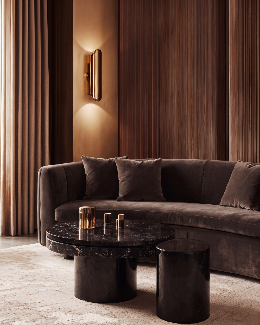 Warm modern living room with a curved cognac sofa, black marble table, and wood paneling in golden light — interior design by Jacqueline Row, Atlanta.