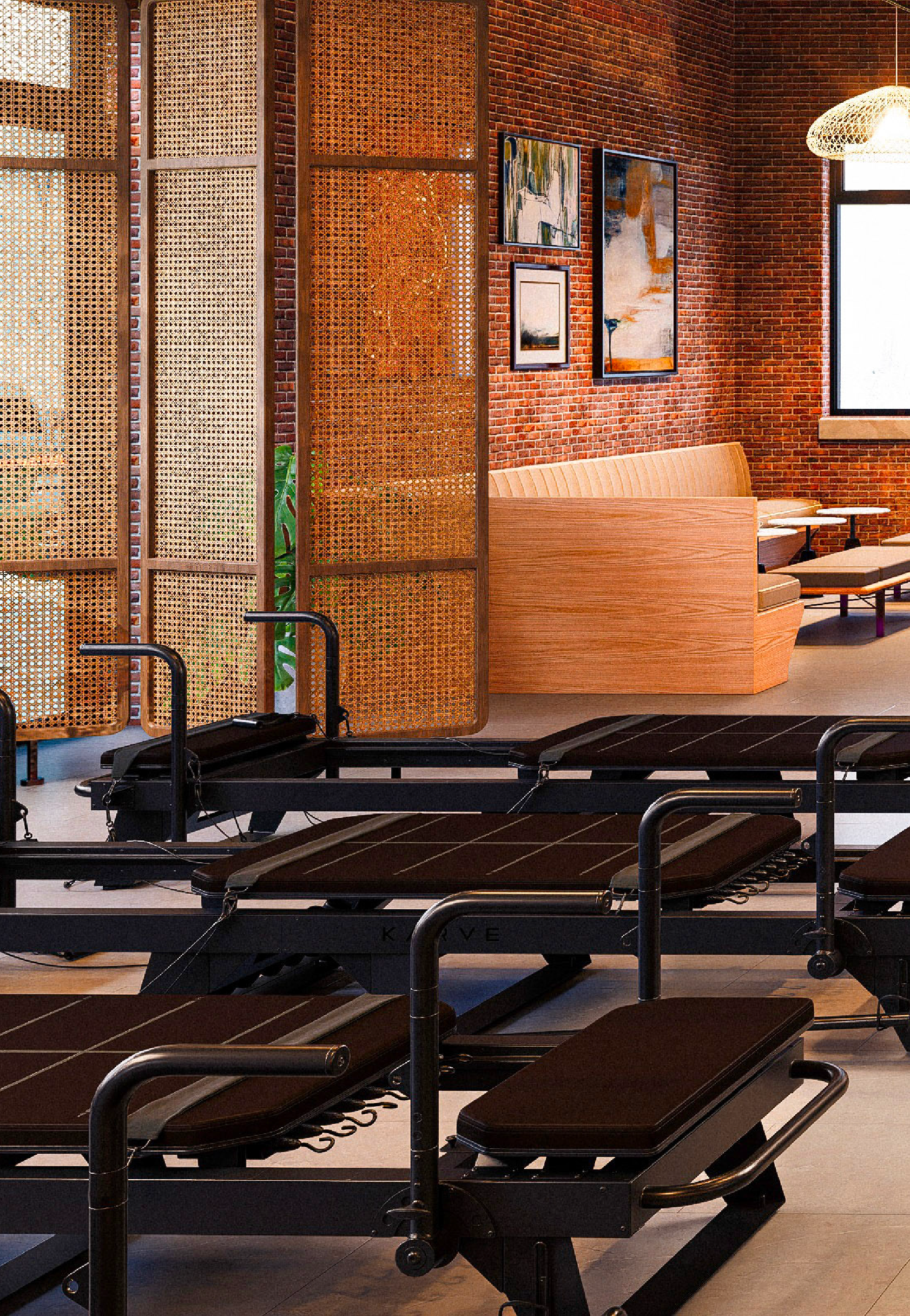 Interior of a gym or fitness spa with massage tables and a wooden partition, brick wall, framed artwork, and a window with natural light.