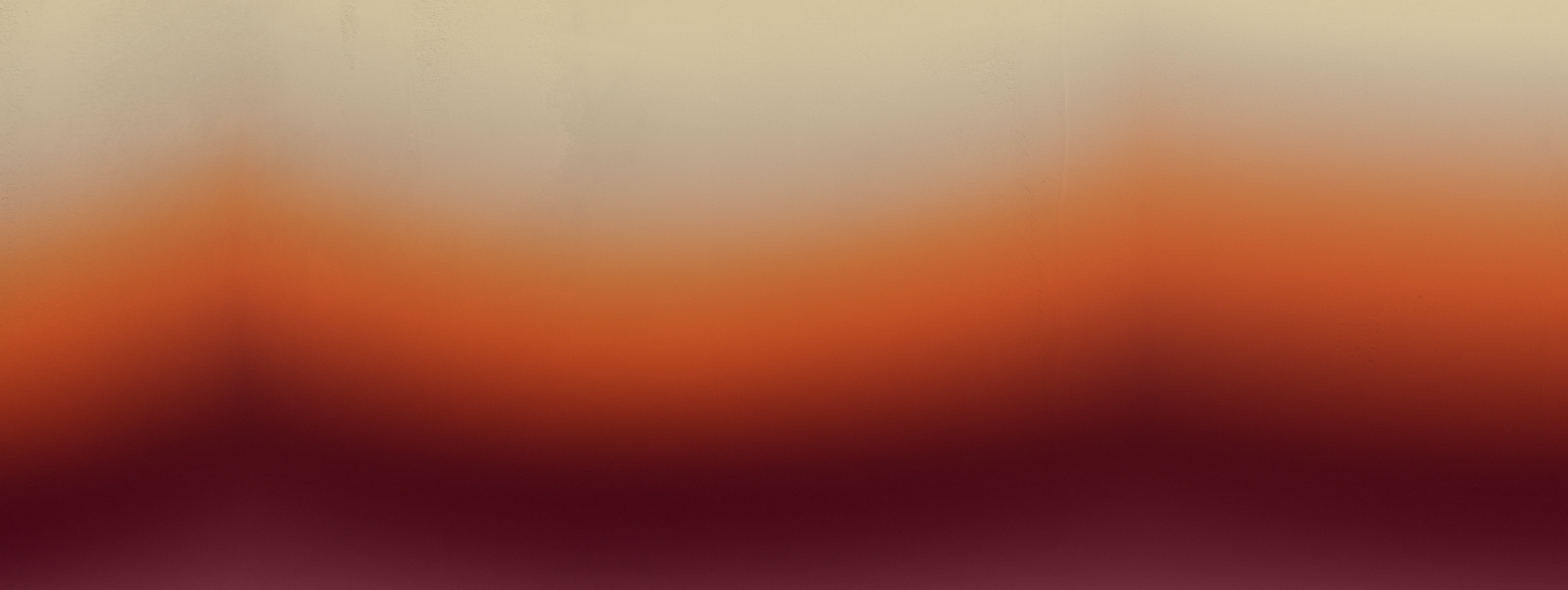 Blurred image with gradient colors from light beige at the top to red at the bottom and dark shades in between.