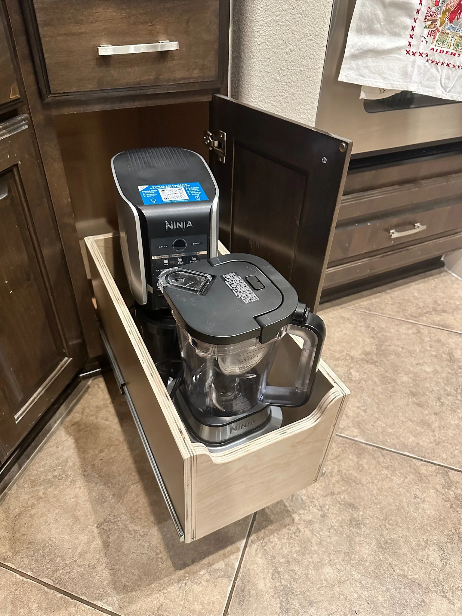 A coffee maker placed inside a wooden cabinet on a small wooden stand in a kitchen.