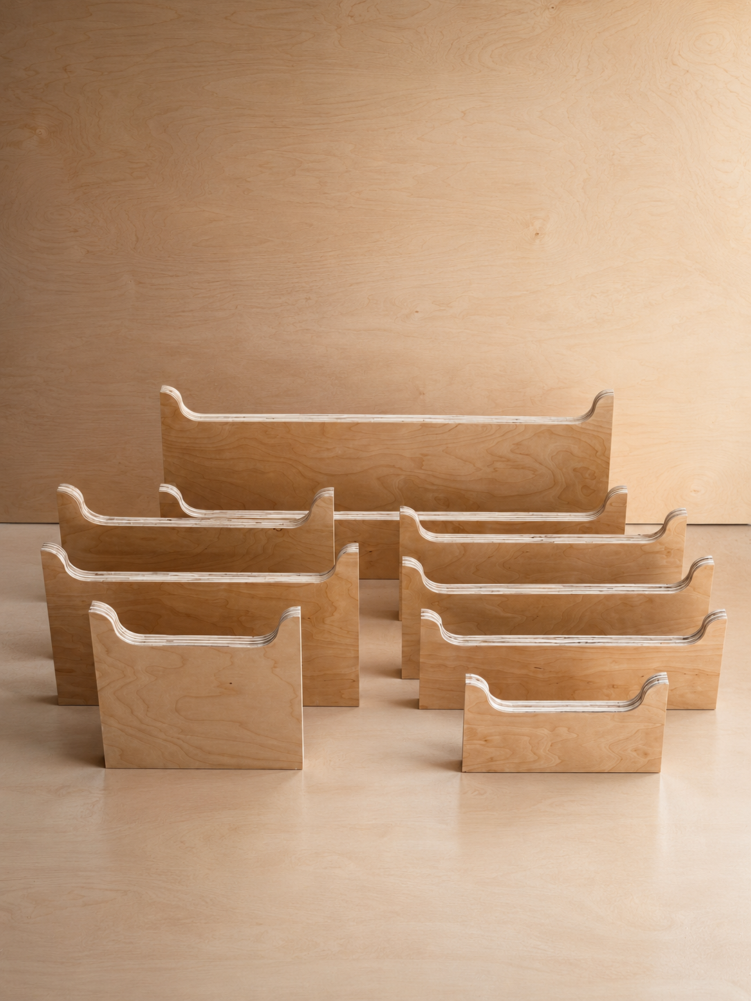Six wooden magazine or file organizers arranged in two rows on a light wooden surface with a wooden panel background.